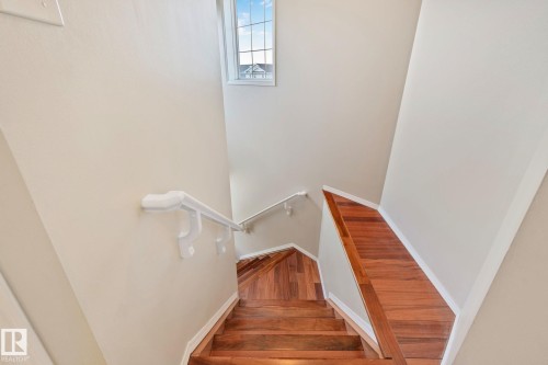 Staircase with wood-finish treads and risers, featuring a white handrail and a window with grid detailing - 3769 21 Street Nw, Edmonton, AB - Indoor Photo Showing Other Room