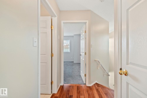 Hallway featuring wood-finish flooring, white panel doors, and neutral wall paint - 3769 21 Street Nw, Edmonton, AB - Indoor Photo Showing Other Room
