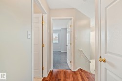 Hallway featuring wood-finish flooring, white panel doors, and neutral wall paint - 