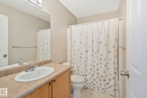 Bathroom featuring a wood-finish vanity with an integrated sink and laminate countertop - 3769 21 Street Nw, Edmonton, AB - Indoor Photo Showing Bathroom