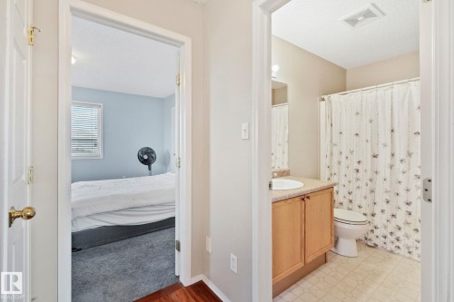 Bathroom featuring a light wood-finish vanity with a drop-in sink, an overhead mirror, a toilet, and a shower with a patterned curtain - 3769 21 Street Nw, Edmonton, AB - Indoor Photo Showing Bathroom