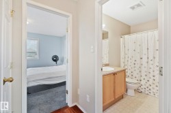 Bathroom featuring a light wood-finish vanity with a drop-in sink, an overhead mirror, a toilet, and a shower with a patterned curtain - 