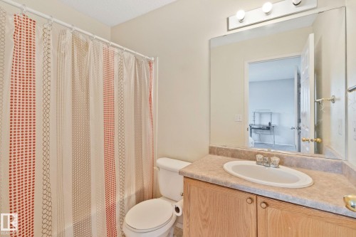 Bathroom featuring a vanity with a laminate countertop, integrated sink, and wood-finish cabinetry - 3769 21 Street Nw, Edmonton, AB - Indoor Photo Showing Bathroom