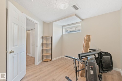 Interior room featuring wood-finish flooring, light neutral wall paint, and a white paneled door - 3769 21 Street Nw, Edmonton, AB - Indoor Photo Showing Other Room
