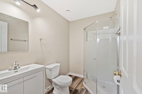 Modern bathroom featuring a glass-enclosed shower, white vanity with integrated sink, chrome fixtures, and wood-finish flooring - 3769 21 Street Nw, Edmonton, AB - Indoor Photo Showing Bathroom
