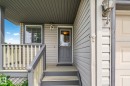 Covered front porch featuring wood steps and railing, gray siding, and a paneled entry door with an upper glass insert - 3769 21 Street Nw, Edmonton, AB  - Outdoor With Exterior 