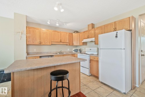 Kitchen featuring a center island, wood-finish cabinetry, tile flooring, and track lighting - 3769 21 Street Nw, Edmonton, AB - Indoor Photo Showing Kitchen With Double Sink