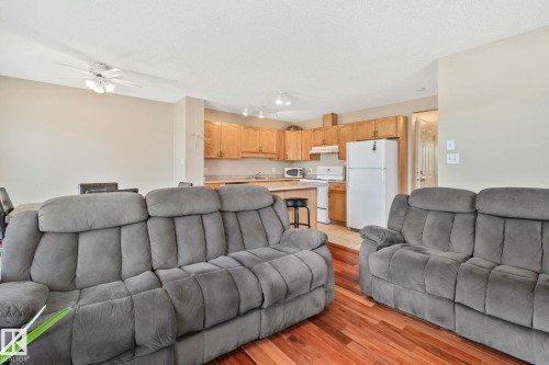 Open-concept living space featuring wood-finish flooring, a kitchen with wood cabinetry and light countertops, and a dining area - 3769 21 Street Nw, Edmonton, AB - Indoor Photo Showing Living Room