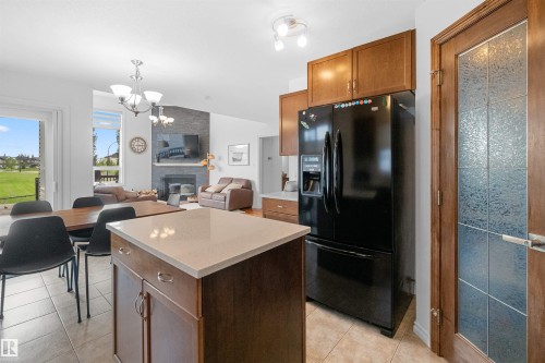 Open-concept living space featuring a central kitchen island with countertop, tile flooring, and a black French door refrigerator - 6515 37 Avenue, Beaumont, AB - Indoor Photo Showing Other Room