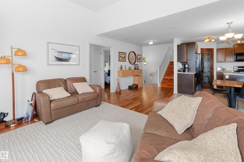 Open-concept living space featuring wood-finish flooring, recessed lighting, and a kitchen with dark cabinetry and stainless steel appliances - 6515 37 Avenue, Beaumont, AB - Indoor Photo Showing Living Room