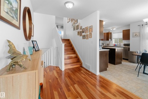 Hardwood flooring, white painted walls, white spindle staircase, recessed lighting, and kitchen with stainless steel appliances - 6515 37 Avenue, Beaumont, AB - Indoor