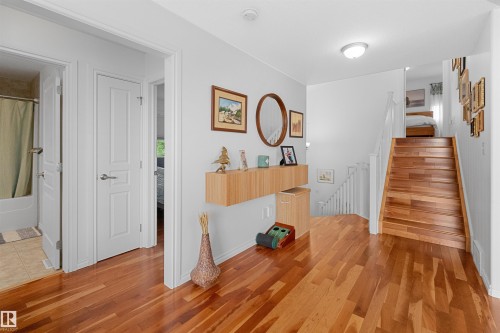 Hardwood flooring throughout, white interior doors with satin nickel hardware, and a staircase with wood-finish treads and white risers - 6515 37 Avenue, Beaumont, AB - Indoor Photo Showing Other Room