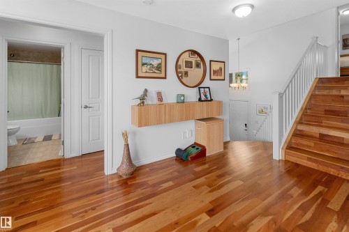 Wood-finish flooring throughout, with a wood staircase featuring white risers and railings - 6515 37 Avenue, Beaumont, AB - Indoor Photo Showing Other Room