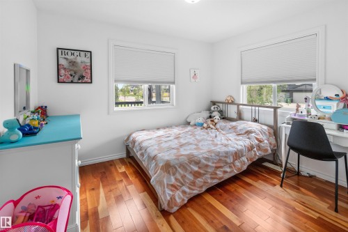 Hardwood flooring, painted white walls, and two windows with blinds - 6515 37 Avenue, Beaumont, AB - Indoor Photo Showing Bedroom