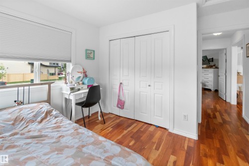 Hardwood flooring, white bi-fold closet doors, white window trim, and white cellular window shades - 6515 37 Avenue, Beaumont, AB - Indoor Photo Showing Bedroom