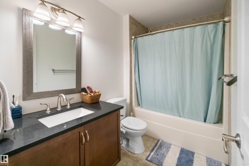 Vanity with dark countertop and undermount sink - 6515 37 Avenue, Beaumont, AB - Indoor Photo Showing Bathroom