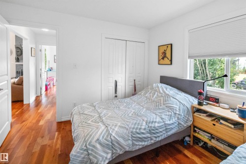 Hardwood flooring, white walls, white trim, recessed window with white blinds, and a built-in closet with double doors - 6515 37 Avenue, Beaumont, AB - Indoor Photo Showing Bedroom