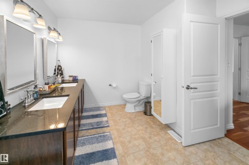Dual vanity with dark wood-finish cabinetry, integrated sinks, and dark countertops - 6515 37 Avenue, Beaumont, AB - Indoor Photo Showing Bathroom