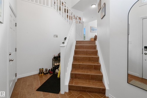 Tiled flooring entry with white paneled door and staircase featuring white balusters and handrail - 6515 37 Avenue, Beaumont, AB - Indoor Photo Showing Other Room