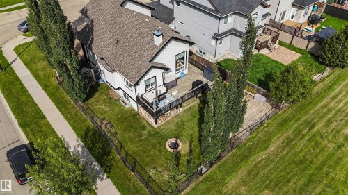 Expansive backyard featuring a multi-level wood deck, a built-in fire pit, and a black metal fence - 6515 37 Avenue, Beaumont, AB - Outdoor