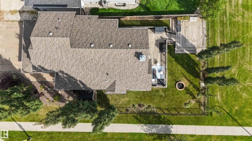 Shingled roof with multiple gables, extensive wood decking, fenced backyard, manicured lawn, and a fire pit - 6515 37 Avenue, Beaumont, AB - Outdoor
