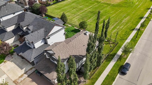 Shingled roofline, light-toned exterior siding, mature trees, concrete sidewalk, and paved road access - 6515 37 Avenue, Beaumont, AB - Outdoor