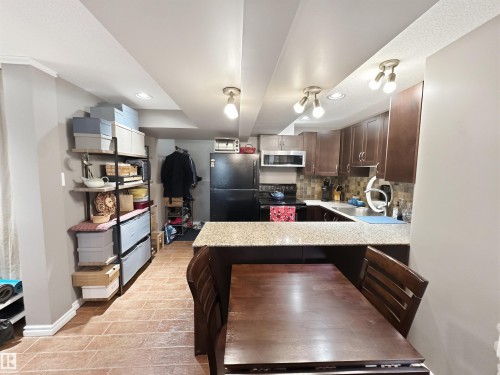 Kitchen featuring wood-finish cabinetry, stainless steel sink, and a multi-tone tile backsplash - 6515 37 Avenue, Beaumont, AB - Indoor