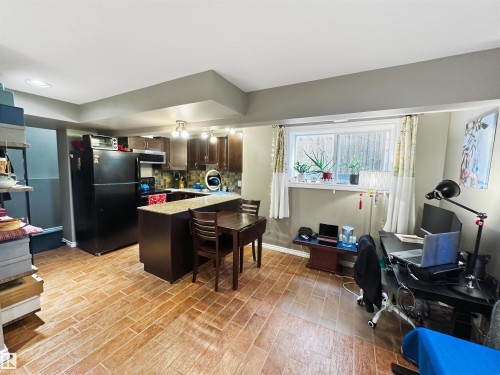 Kitchen with wood-finish cabinetry, stone-look countertops, and a tile backsplash - 6515 37 Avenue, Beaumont, AB - Indoor