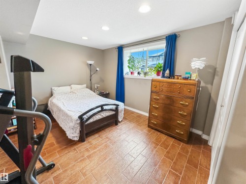 Recessed ceiling lighting, tiled flooring, window with blue drapery, painted walls, and a built-in closet with a white door - 6515 37 Avenue, Beaumont, AB - Indoor Photo Showing Bedroom