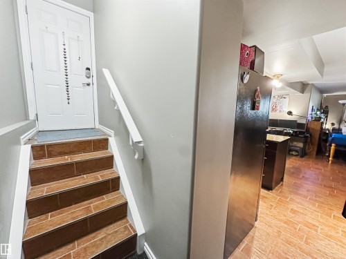 Entryway featuring a white paneled door, wood-finish tile stairs, white handrail, and light gray wall paint - 6515 37 Avenue, Beaumont, AB - Indoor Photo Showing Other Room
