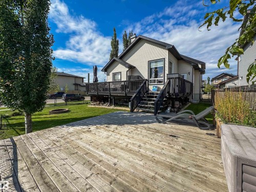 Expansive wood-plank deck with a raised planter, leading to a manicured lawn and a multi-level composite deck - 6515 37 Avenue, Beaumont, AB - Outdoor With Deck Patio Veranda