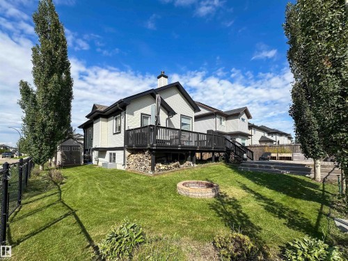 Manicured lawn, elevated wood deck, stone-lined fire pit, and tiered landscaping - 6515 37 Avenue, Beaumont, AB - Outdoor With Deck Patio Veranda