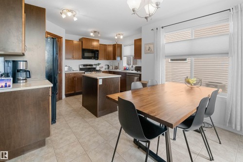 Kitchen featuring wood-finish cabinetry, a central island with countertop, stainless steel appliances, and tiled flooring - 6515 37 Avenue, Beaumont, AB - Indoor