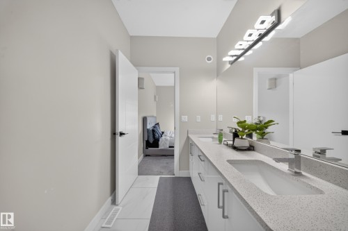 Double vanity with integrated sinks, speckled countertop, and chrome faucets - 4301 38 St, Beaumont, AB - Indoor Photo Showing Bathroom