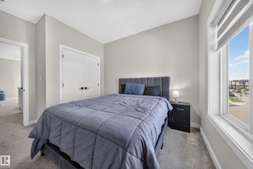 Spacious bedroom with light gray walls, plush carpet flooring, a large window, and double bi-fold closet doors - 4301 38 St, Beaumont, AB - Indoor Photo Showing Bedroom
