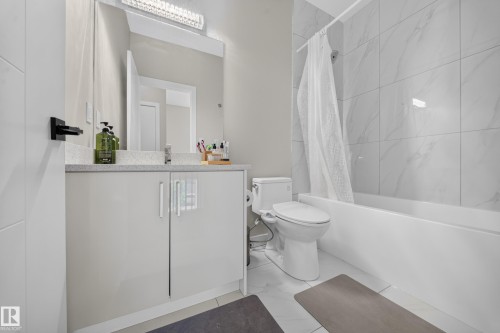 White vanity with a light-colored countertop, large mirror, and overhead light fixture - 4301 38 St, Beaumont, AB - Indoor Photo Showing Bathroom