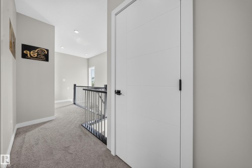 Recessed lighting, light gray wall paint, gray carpet flooring, contemporary white door with black hardware, and black metal balusters - 4301 38 St, Beaumont, AB - Indoor Photo Showing Other Room