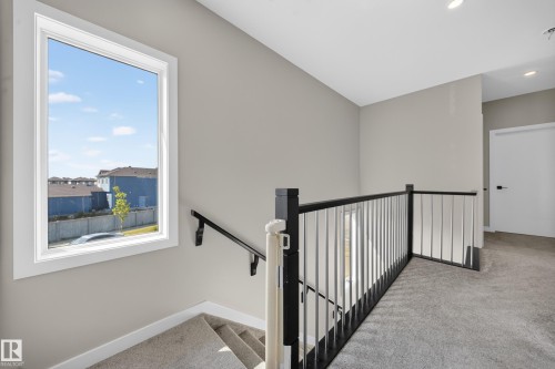 Staircase featuring dark wood handrails, white balusters, and gray carpeting - 4301 38 St, Beaumont, AB - Indoor Photo Showing Other Room