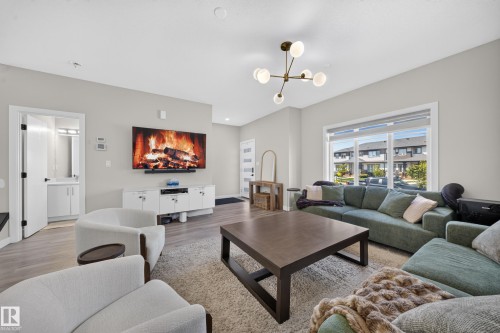 Spacious living area featuring wood-finish flooring, a contemporary chandelier, and a large window - 4301 38 St, Beaumont, AB - Indoor Photo Showing Living Room