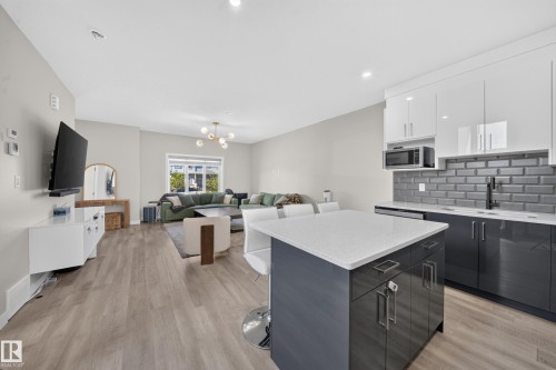 Wood-finish flooring, recessed lighting, and a modern kitchen island with a light-toned countertop - 4301 38 St, Beaumont, AB - Indoor Photo Showing Kitchen With Upgraded Kitchen