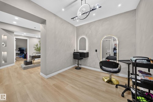 Light wood-finish flooring, recessed ceiling lighting, wall-mounted light fixture, arched wall mirrors with integrated lighting, and built-in wall niches with accent lighting - 4301 38 St, Beaumont, AB - Indoor Photo Showing Other Room