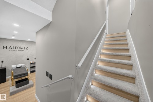 Staircase featuring carpeted treads, wood-finish risers, integrated step lighting, and a white handrail - 4301 38 St, Beaumont, AB - Indoor Photo Showing Other Room