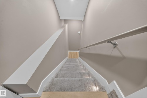 Staircase featuring carpeted treads, wood-finish flooring at landing, a wall-mounted handrail, and integrated step lighting - 4301 38 St, Beaumont, AB - Indoor Photo Showing Other Room