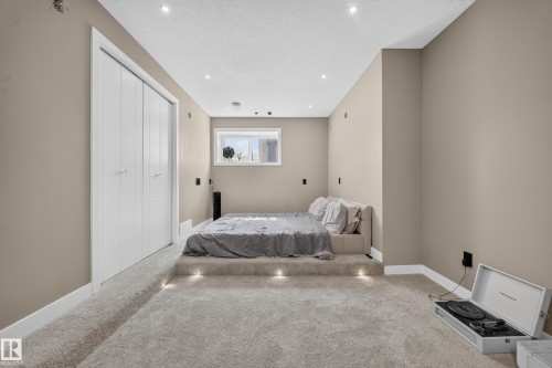 Recessed ceiling lighting, elevated platform with integrated lighting, window, white bifold closet doors, and carpeted flooring - 4301 38 St, Beaumont, AB - Indoor Photo Showing Bedroom