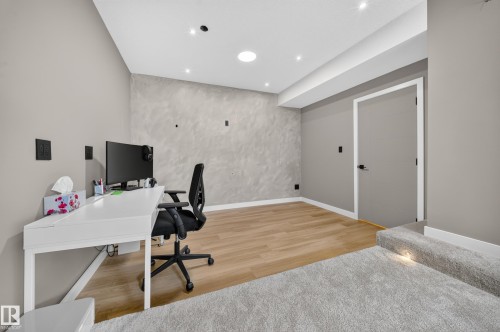 Modern home office featuring a dedicated workspace with white built-in desk, engineered wood-finish flooring, and recessed ceiling lighting - 4301 38 St, Beaumont, AB - Indoor Photo Showing Office