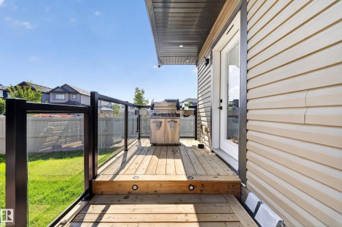 Wood deck with integrated lighting, glass panel railing with dark metal posts, light-toned horizontal siding, and a glass-paneled exterior door - 4301 38 St, Beaumont, AB - Outdoor With Deck Patio Veranda With Exterior