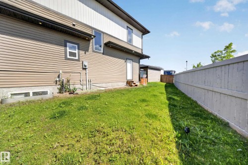Exterior siding in a two-tone finish, featuring a privacy fence, a ground-level door, and an exterior light fixture - 4301 38 St, Beaumont, AB - Outdoor With Exterior