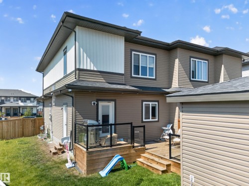 Expansive backyard featuring a manicured lawn, a wooden deck with glass railings, and a privacy fence - 4301 38 St, Beaumont, AB - Outdoor With Deck Patio Veranda With Exterior