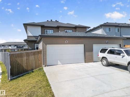 Two-car attached garage with white overhead doors, concrete driveway, and brown horizontal siding - 4301 38 St, Beaumont, AB - Outdoor