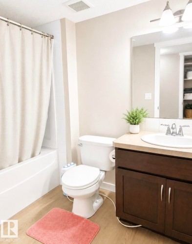 Bathroom featuring a vanity with dark wood-finish cabinetry, a light-colored countertop, and a white drop-in sink - 5135 1A Avenue Sw, Edmonton, AB - Indoor Photo Showing Bathroom